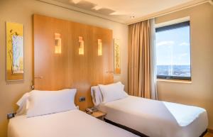 duas camas num quarto de hotel com uma janela em Abba Madrid em Madri