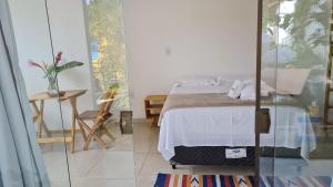 two images of a bedroom with a bed and a table at Vila Pitangueira - Flat Terra - No centro de Serra Grande com Piscina, Jacuzzi, Internet Veloz in Serra Grande
