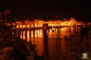 a city at night with a large body of water at Hotel Casa Arizzoli in Cannobio