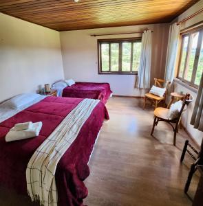 a bedroom with two beds and a chair and windows at Pousada Bliss House - Opções de suites com hidromassagem in Campos do Jordão
