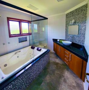 La grande salle de bains est pourvue d'une baignoire et d'un lavabo. dans l'établissement Pousada Bliss House - Opções de suites com hidromassagem, à Campos do Jordão