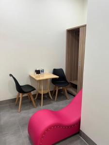 ein Zimmer mit einem Tisch, Stühlen und einem rosa Sofa in der Unterkunft Hotel Hòa Bình in Bình Châu