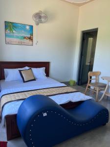ein Schlafzimmer mit einem Bett mit einer blauen Ottomane darauf in der Unterkunft Hotel Hòa Bình in Bình Châu