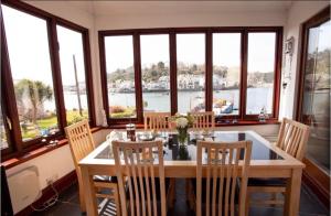 a dining room with a table and chairs and windows at Tabs Cottage in Fowey