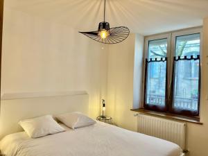 een slaapkamer met een wit bed en een kroonluchter bij Le Cours Ladauge in La Rochelle
