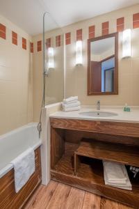 a bathroom with a sink and a tub and a mirror at Résidence Pierre & Vacances Le Belmont in Arc 1800