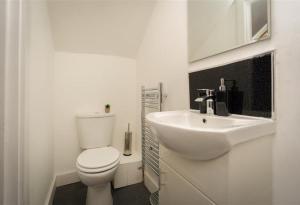 Baño blanco con aseo y lavamanos en King St Contractor Accommodation 6 bed 6 bath free parking for vans en Wallasey