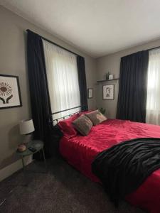 a bedroom with a red bed and two windows at Cozy vintage getaway minutes from downtown in Lincoln +8 photos