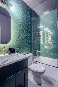 a green tiled bathroom with a toilet and a sink at Elegant Black Modern in Lincoln