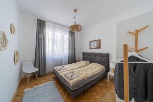een slaapkamer met een bed, een stoel en een raam bij BohoHome next to the main street in Sofia