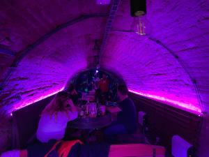 a group of people sitting at a table in a purple tunnel at Chaloupka víno sklep U Palečků in Zaječí +83 photos