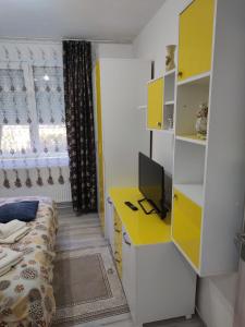 a bedroom with a yellow desk and a bed at Family Rooms Hunedoara in Hunedoara