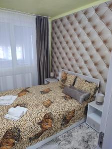 a bedroom with a bed with a large padded headboard at Family Rooms Hunedoara in Hunedoara +5 photos