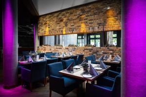 a restaurant with tables and chairs with purple lighting at GINN Hotel Berlin Potsdam in Teltow
