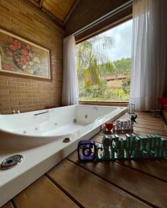 a bath tub in a room with a large window at Chalés Villa Caravaggio in Santa Teresa