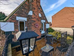 a brick house with a table and chairs on a patio at Chocbox Cottage - 2 bedroom chocbox cottage with hottub and log fire in Pocklington