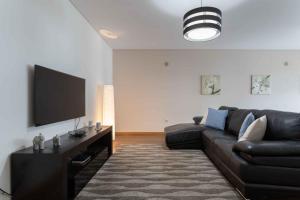 uma sala de estar com um sofá preto e uma televisão de ecrã plano em Modern & Elegant 2 bedroom in Amadora by GT House na Amadora
