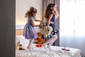 two young girls playing on a bed with stuffed animals at ibis Bucharest Politehnica in Bucharest