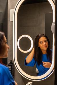 a woman is looking at her reflection in a mirror at ibis Bucharest Politehnica in Bucharest