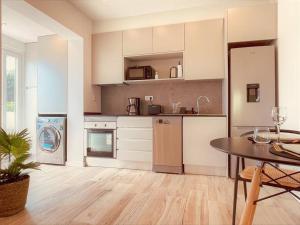 Cozy apartment with private courtyard في Barcarena: مطبخ فيه دواليب بيضاء وطاولة فيه