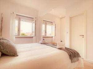 1 dormitorio blanco con 1 cama blanca grande y 2 almohadas en Cozy apartment with private courtyard, en Barcarena