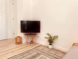TV de pantalla plana en la pared de la sala de estar. en Cozy apartment with private courtyard, en Barcarena