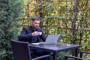a man sitting at a table with a laptop computer at ibis Bucharest Politehnica in Bucharest