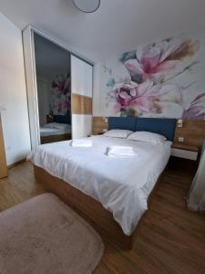 a bedroom with a large bed with a painting on the wall at Apartman Blago Zlatibora in Zlatibor