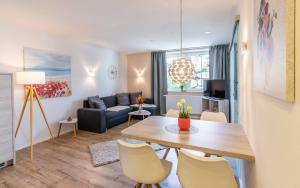 een woonkamer met een tafel en stoelen en een bank bij Das Maximilian - Feines Landhotel am Schliersee in Schliersee