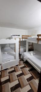a room with white bunk beds on a wooden floor at Hostel Rincon del mar Ebenezer in San Onofre