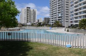 a white fence around a swimming pool with tall buildings at Departamento Playa Herradura Primera Línea in Coquimbo