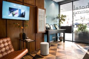 een lobby met een stoel en een tv aan de muur bij Hotel Emma in Rotterdam