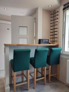 uma cozinha com quatro cadeiras verdes num balcão em Loueurdappart - Maison Calme Entre Mer et Commerces Tout à Pied em La Baule