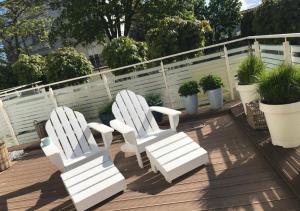 two white chairs sitting on a deck with potted plants at Playa Baltis Apartamenty Club di Mare in Międzyzdroje