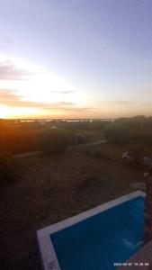 vista su una piscina con il tramonto sullo sfondo di Casa quinta con espectacular vista al rio a General Alvear