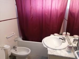 een badkamer met een wastafel en een roze douchegordijn bij La maison de la mer in Setúbal