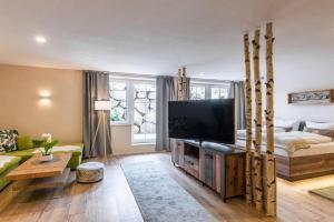 a living room with a television and a couch at Das Maximilian - Feines Landhotel am Schliersee in Schliersee