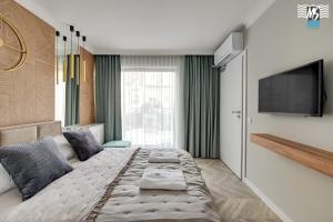 a bedroom with a large bed and a flat screen tv at MS Apartments Rest 1.0 in Sopot