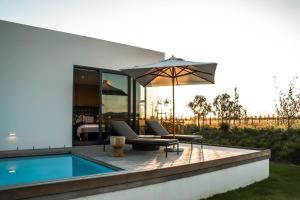 a patio with a swimming pool and an umbrella at Vergenoegd Löw Boutique Hotel & Spa in Somerset West