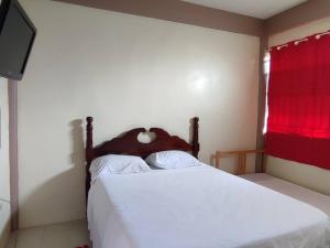 1 dormitorio con cama blanca y cortina roja en Iso’s Vacation Rental Apartment #8, en Portsmouth