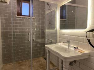 a white bathroom with a sink and a shower at Dionysos 1789 Boutique Hotel in Foca