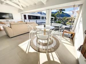 sala de estar con mesa y sillas en el balcón en Acacia Tropical, luxurious Duplex, walkable beach, en Anse Marcel 