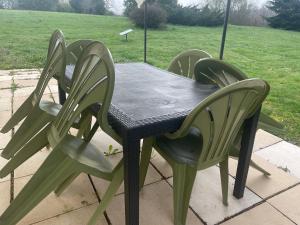 stół z 4 krzesłami wokół niego na patio w obiekcie Le Haouret w mieście Parleboscq