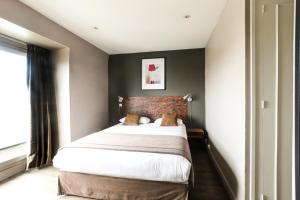 una camera con un grande letto con un muro di mattoni di Hotel Des Cedres a Orléans