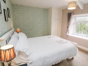 a bedroom with a white bed and a window at Joyces Cottage, 2 Brown Hill in Richmond