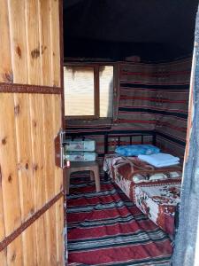 um pequeno quarto com 2 camas e uma janela em Feynan wild camp em Al Khuraybah