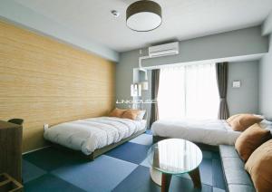 1 dormitorio con 2 camas, sofá y mesa en LINK HOUSE HOTEL - スマート無人ステイ - Unmanned design hotel, en Fukuoka