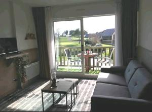a living room with a couch and a large window at Studio Golf piscine D Day in Port-en-Bessin-Huppain