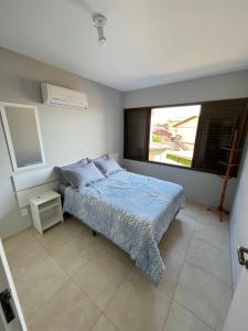 a bedroom with a bed and a large window at Apartamento beira mar em Ponta das Canas in Florianópolis