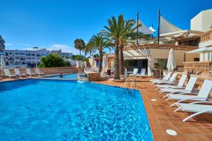 een zwembad met ligstoelen en een resort bij Apartamentos Azul Playa in Cala d´Or